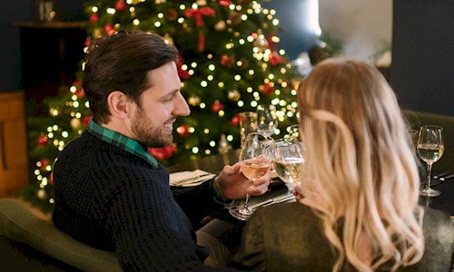 Man and woman drinking wine by a Christmas tree in the Queen Anne Room at Edinburgh Castle