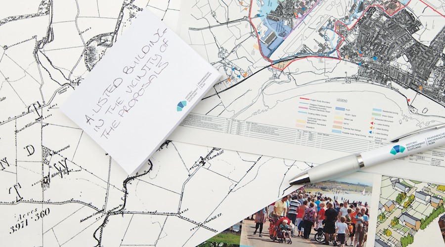 A collage of maps and planning documents sitting on a table, with a pen. Some of the maps are historic, others modern Ordnance Survey versions.