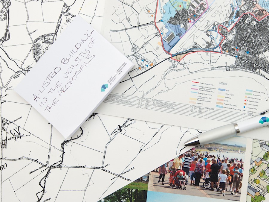 A collage of maps and planning documents sitting on a table, with a pen. Some of the maps are historic, others modern Ordnance Survey versions.