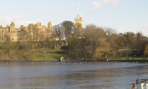 View of a calm loch and a palace surrounded by trees