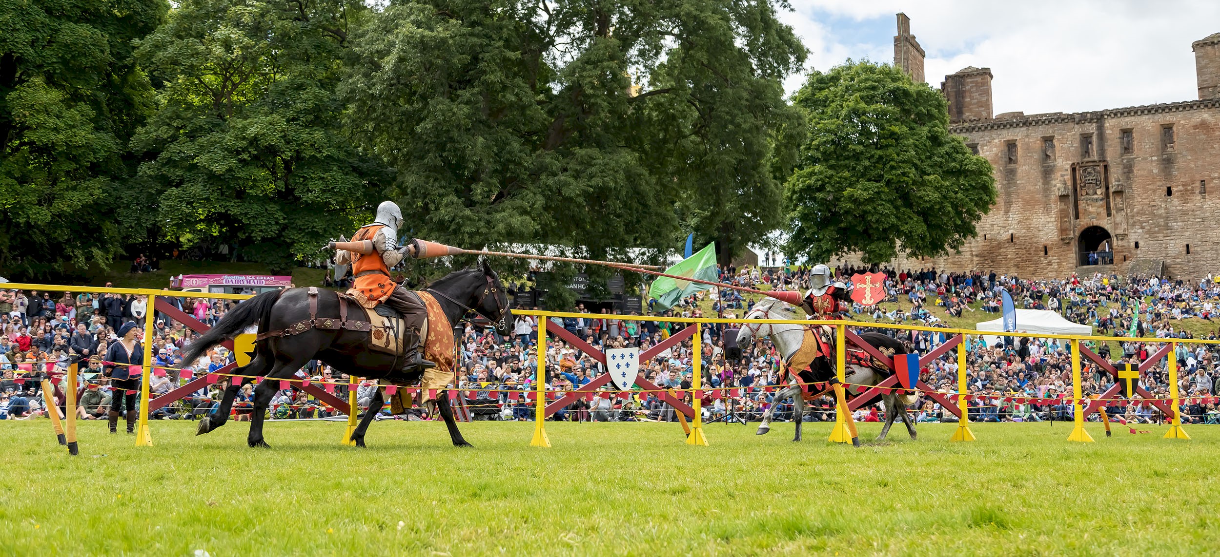 Two knights on horses taking part in a joust and wielding their lances as they approach each other