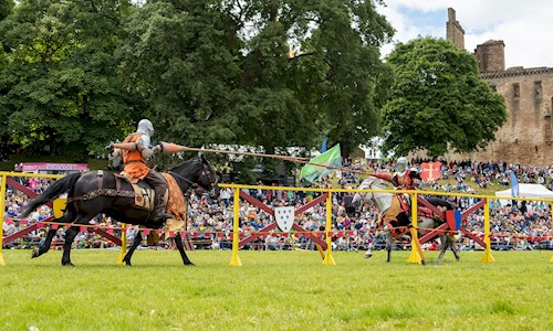 Two knights on horses taking part in a joust and wielding their lances as they approach each other