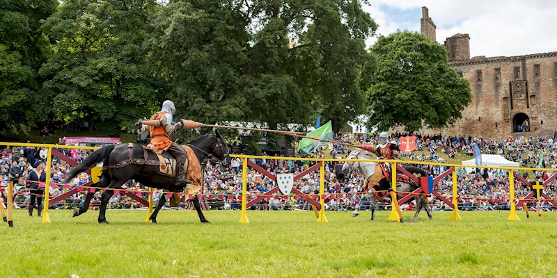 Two knights on horses taking part in a joust and wielding their lances as they approach each other