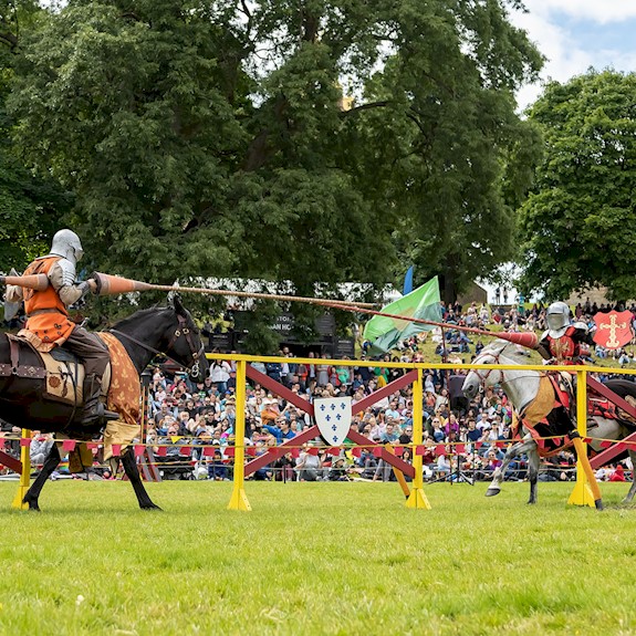 Two knights on horses taking part in a joust and wielding their lances as they approach each other