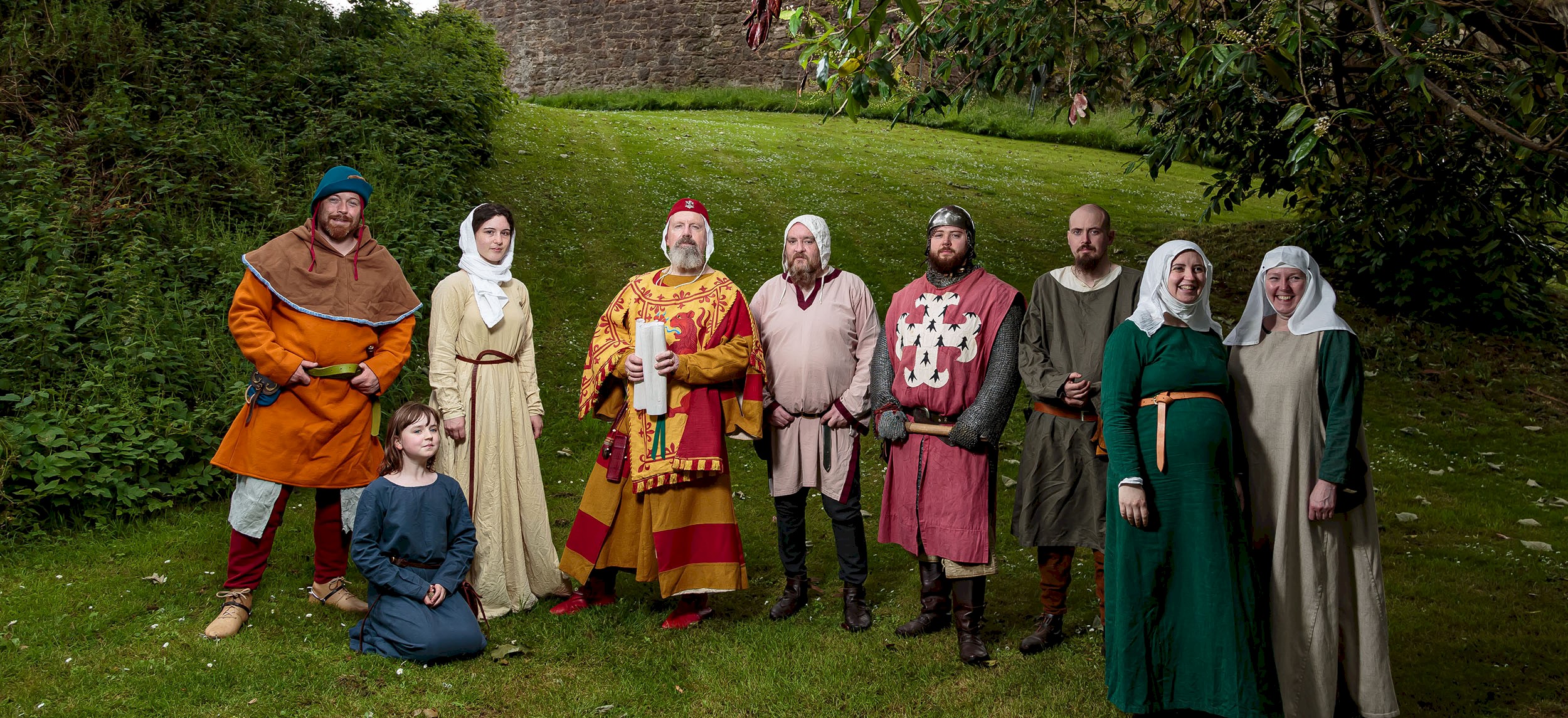 A group of costumed performers posing for the camera in the grounds of a castle