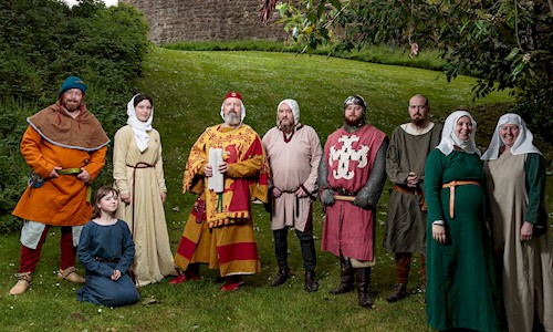 A group of costumed performers posing for the camera in the grounds of a castle