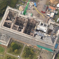 A traditional stone building badly damaged by fire with no roof, crumbling walls and surrounded by scaffolding