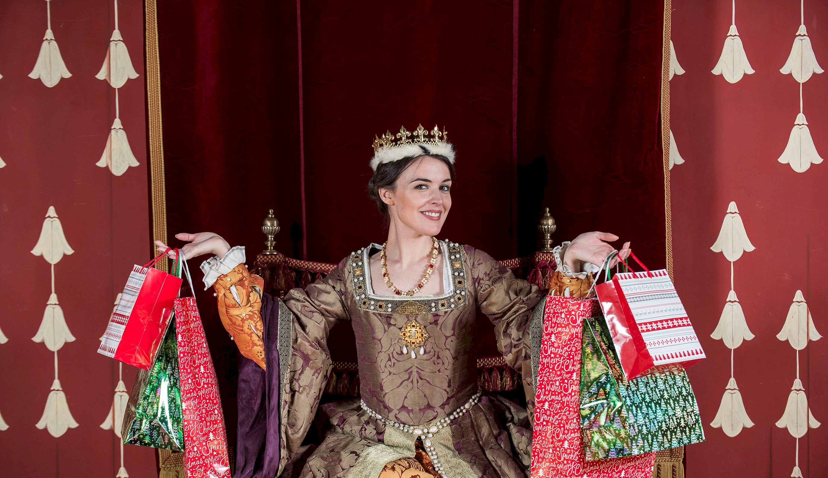 A costumed performer with tinsel round their necks and holding Christmas bags