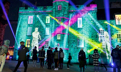 People gathered around enjoying a light display in Crown Square at Edinburgh Castle 