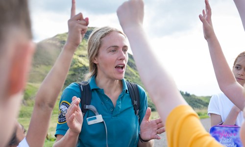 A Park Ranger talking to young people with their hands up