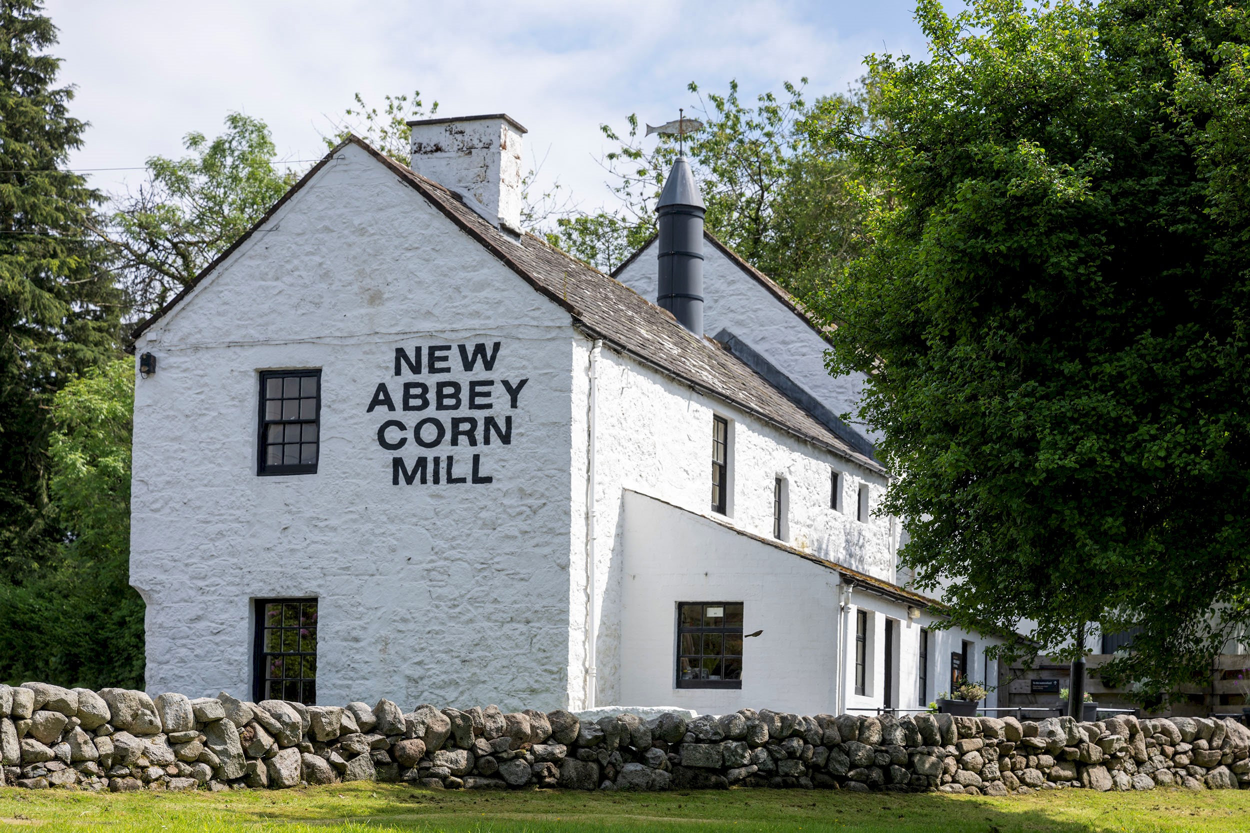 A white brick building with New Abbey Corn Mill painted on the end wall 