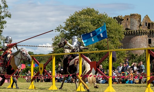 Two knights on horses taking part in a joust and wielding their lances as they approach each other