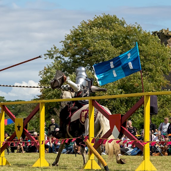 Two knights on horses taking part in a joust and wielding their lances as they approach each other