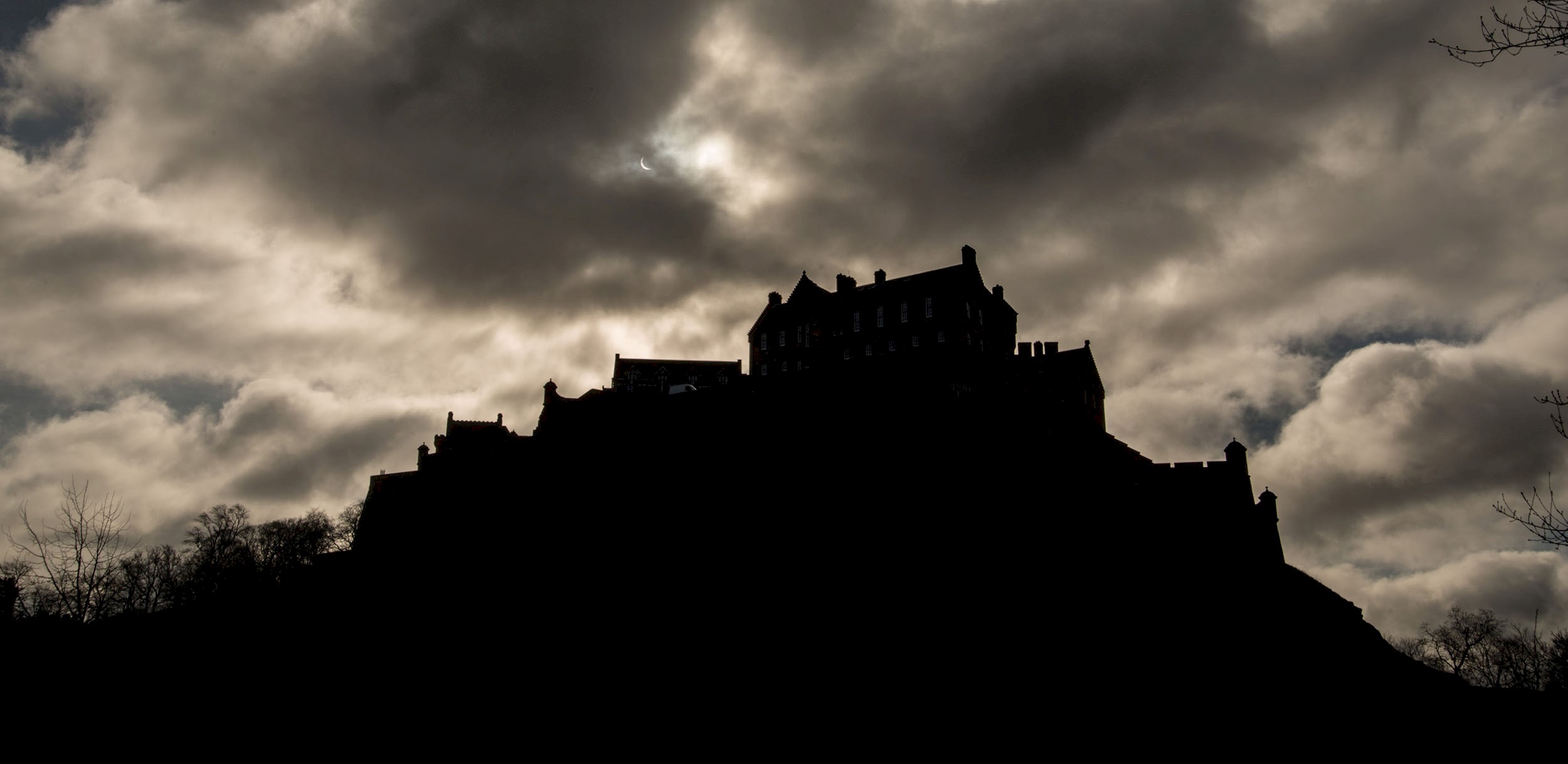 Silhouette of Edinburgh Castle in the dark under lots of cloud