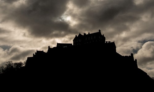 Silhouette of Edinburgh Castle in the dark under lots of cloud