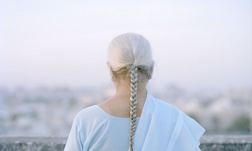 A lady with her back to the camera and her long grey hair in a pleat 