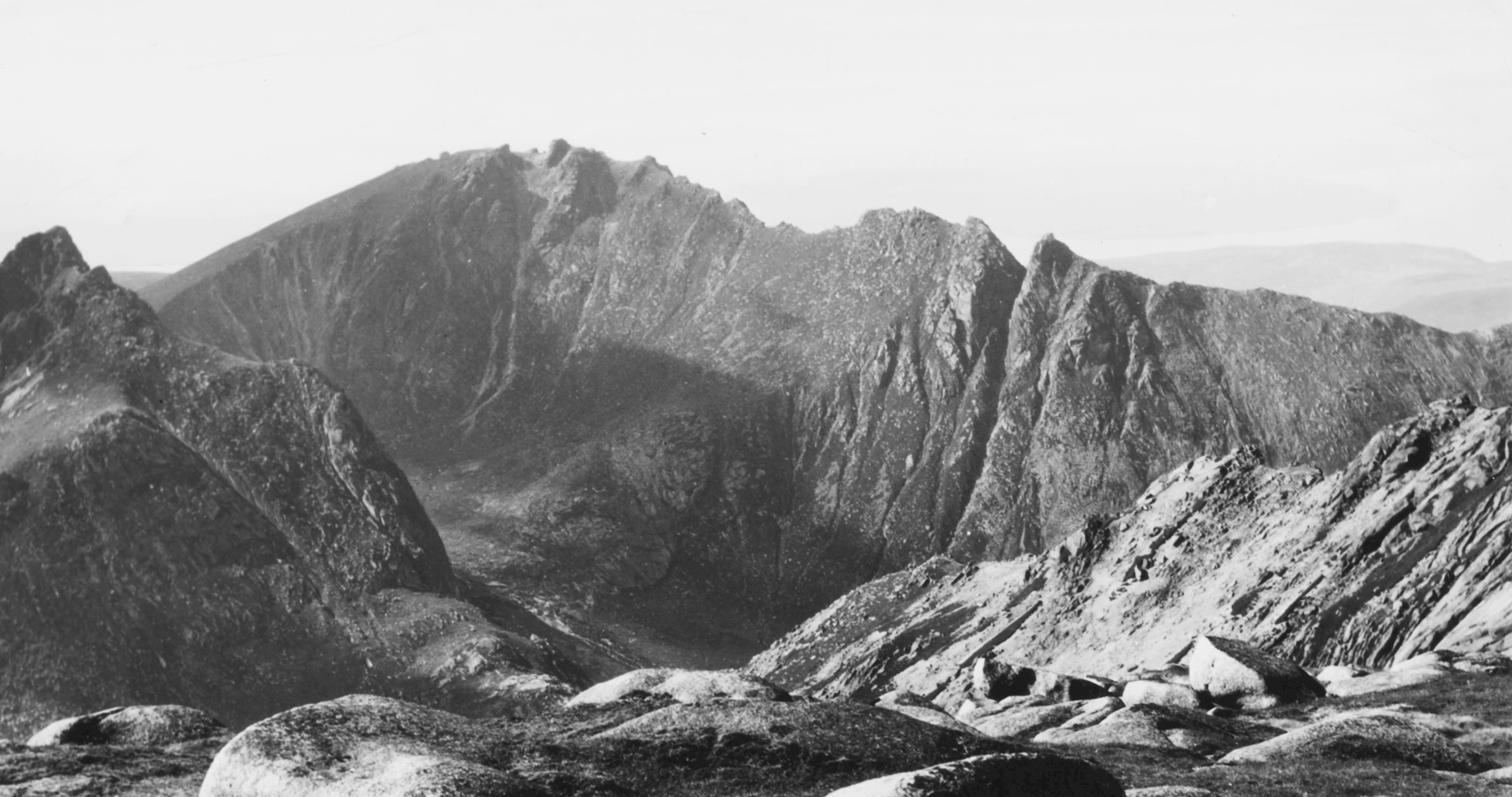 The boulder-strewn surface of Goat Fell summit in the foreground of this view of the famous Sleeping Warrior ridge in the Isle of Arran