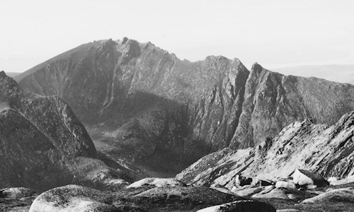 The boulder-strewn surface of Goat Fell summit in the foreground of this view of the famous Sleeping Warrior ridge in the Isle of Arran
