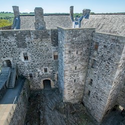 A large, stone square castle with a slate roof