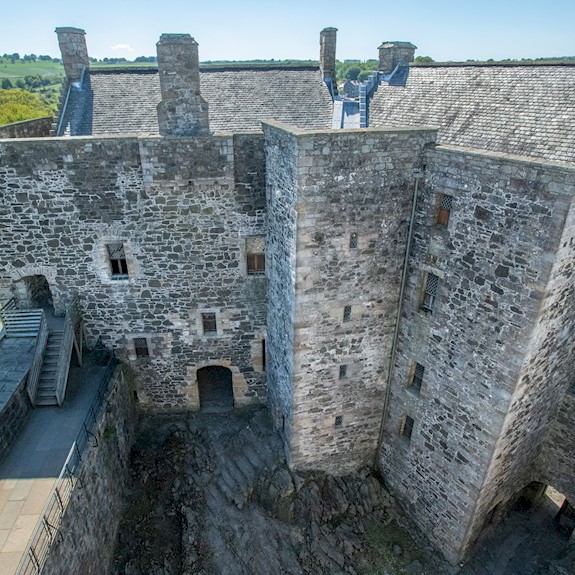 A large, stone square castle with a slate roof