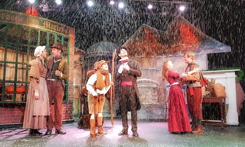actors on stage, singing and dancing in the snow