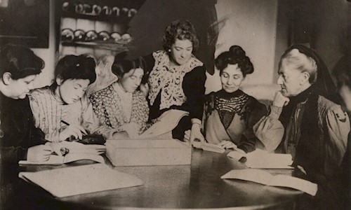 A group of women gathered around a table reading papers. Image © National Portrait Gallery, London. Attribution-NonCommercial-NoDerivs 3.0 Unported (CC BY-NC-ND 3.0)
