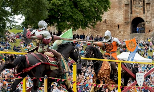 Two knights on horses taking part in a joust and wielding their lances as they approach each other