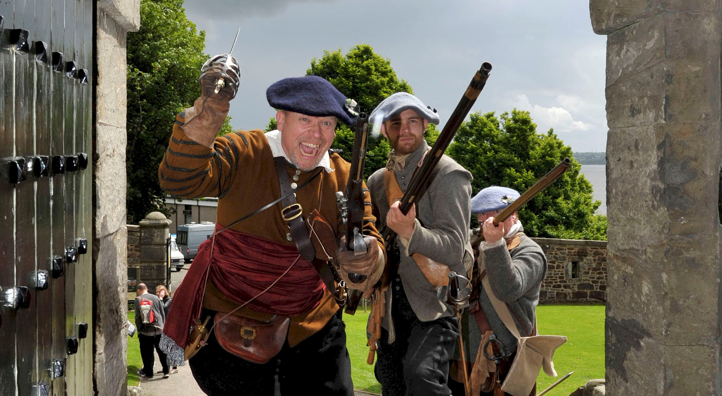 Costumed performers holding weaponry and charging into a castle 