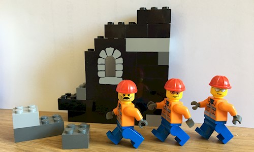 Three Lego figures in front of a Lego built castle