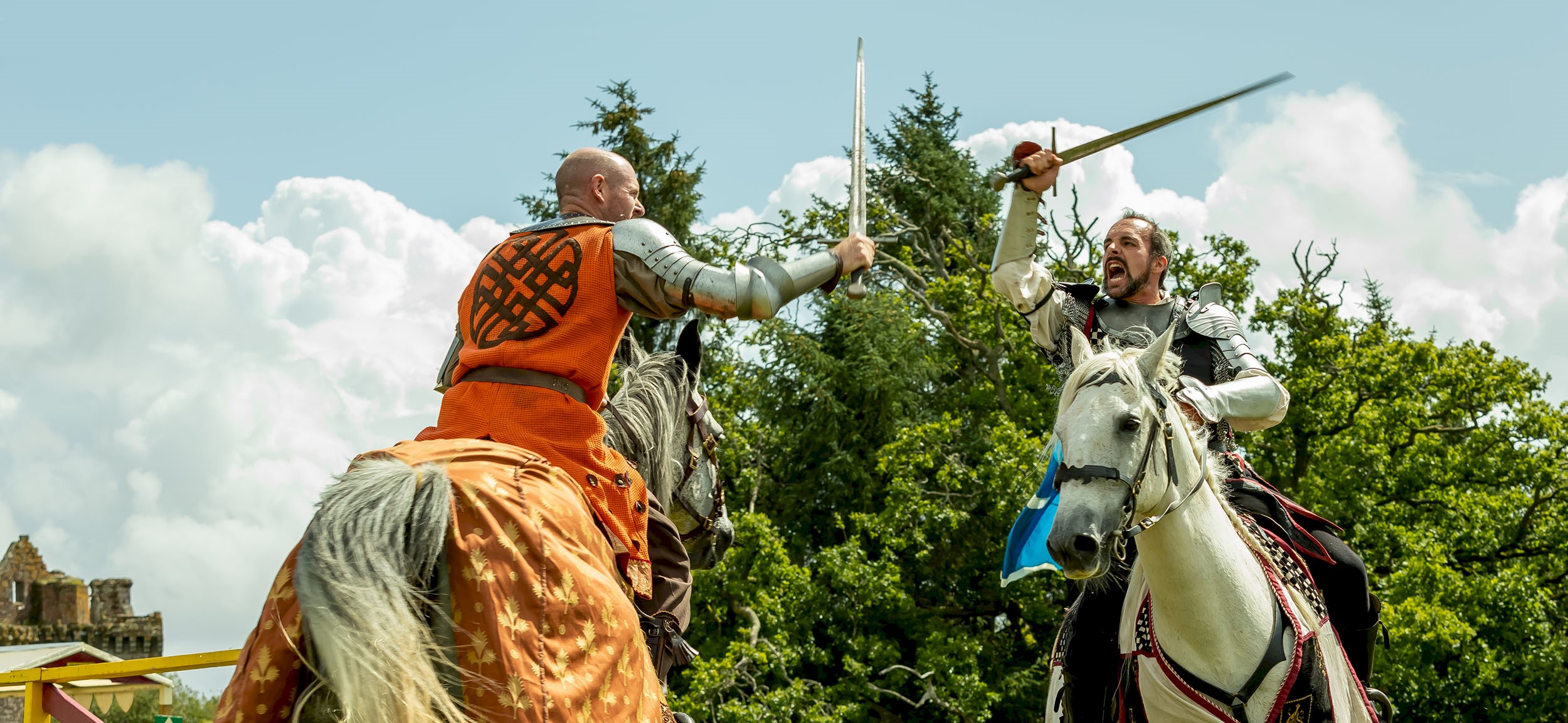Two knights on horses taking part in a joust and wielding their swords at each other