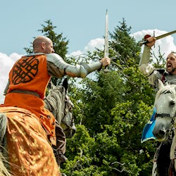 Two knights on horses taking part in a joust and wielding their swords at each other