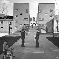 black and white picture of tenement blocks and children playing on bikes and with prams