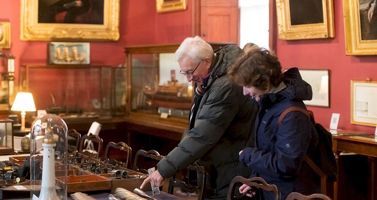 Two people looking at artefacts in a red painted room 