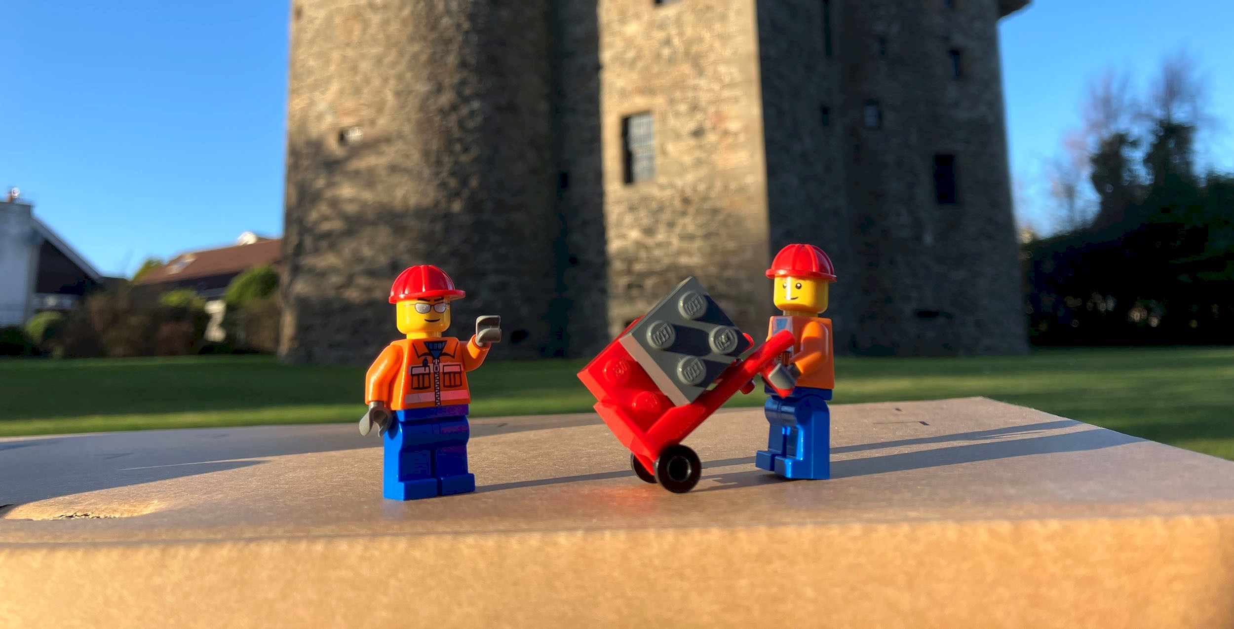 Lego figures standing in front of a castle on sunny day