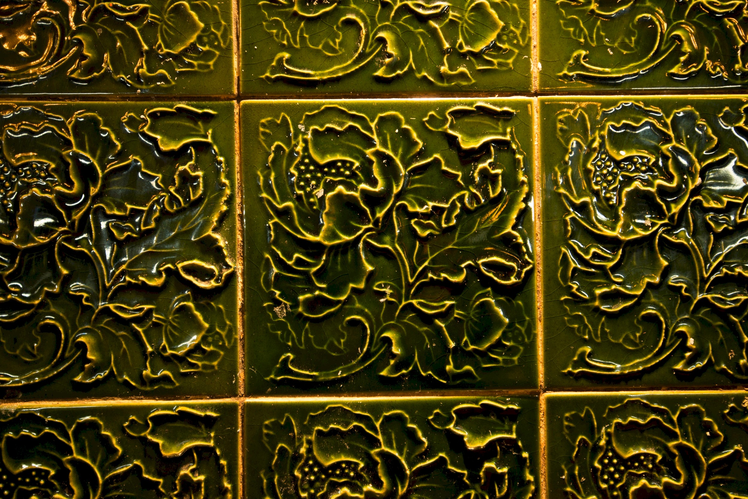 Green glazed wall tiles with a floral pattern sculpted into them