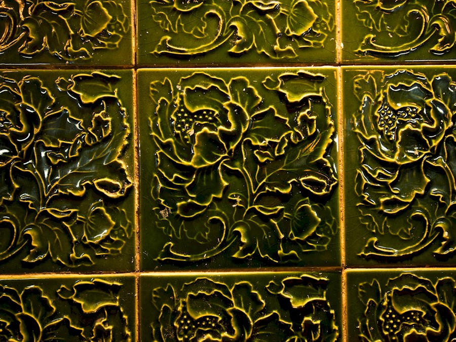 Green glazed wall tiles with a floral pattern sculpted into them