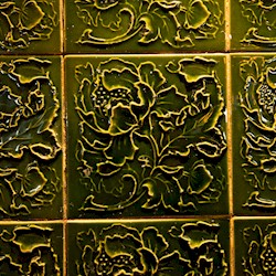 Green glazed wall tiles with a floral pattern sculpted into them