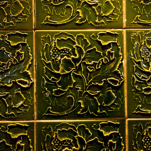 Green glazed wall tiles with a floral pattern sculpted into them
