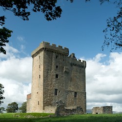 Exterior view of a tower surrounded by lush green grass, blue skies and trees