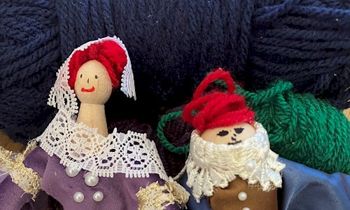 Two peg dolls with balls of wool behind them