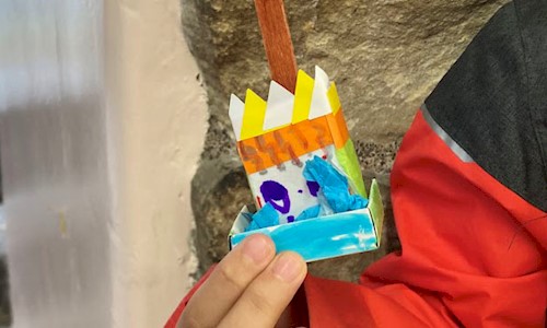 A childs hand holding the mini castle they made