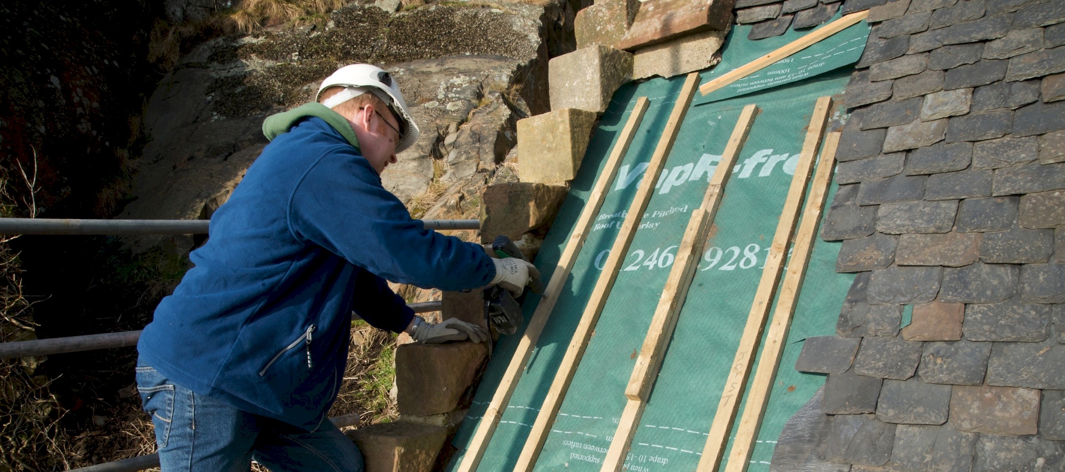 Man inspecting slates on a roof