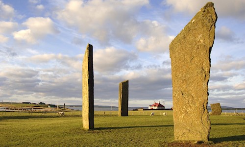 standing stones with a small red roofed cottage in background