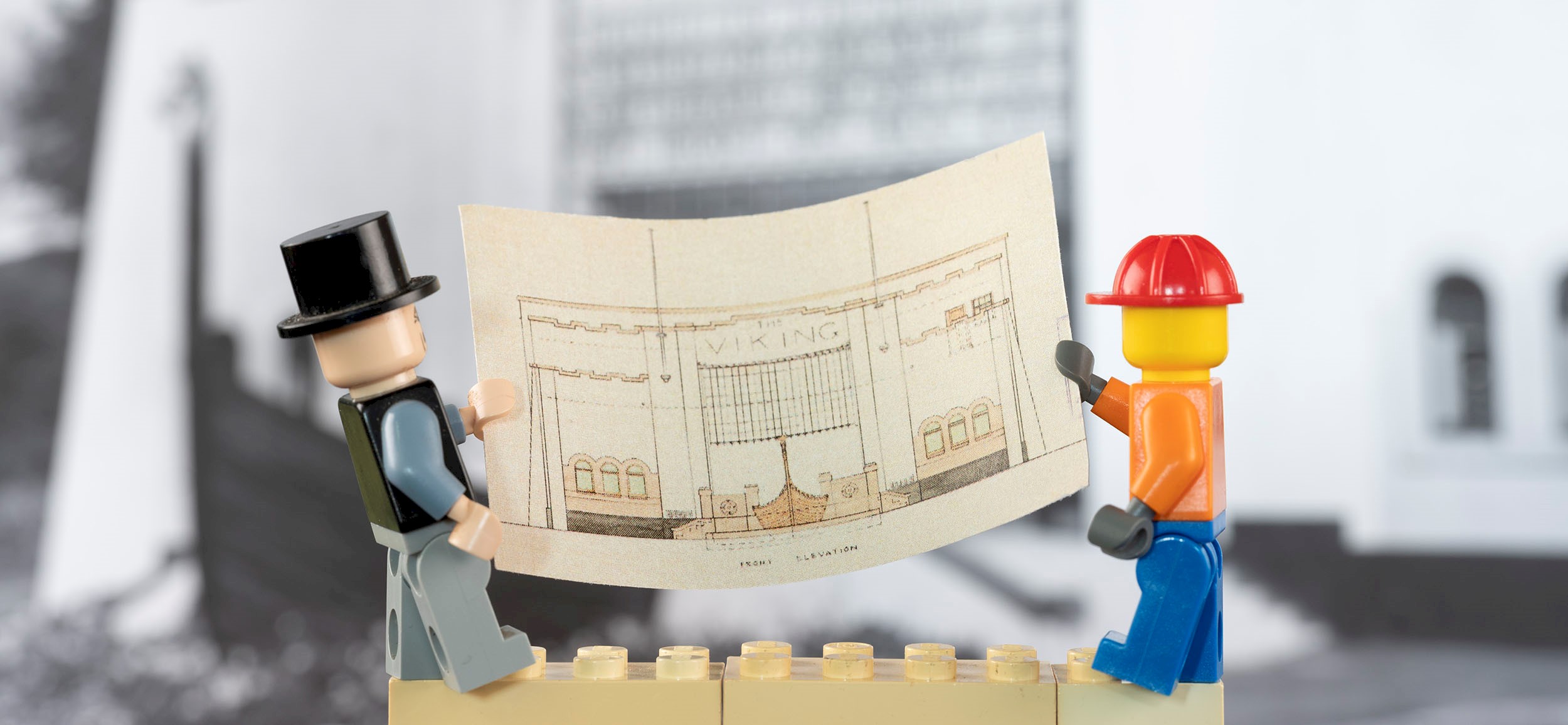 Two lego figures holding a plan of the Viking Cinema.