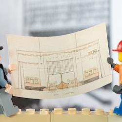Two lego figures holding a plan of the Viking Cinema.