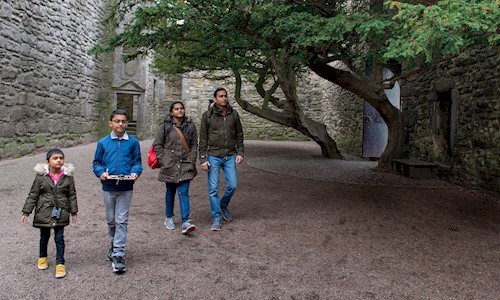 A family in the courtyard at Craigmillar Castle underneath a large tree