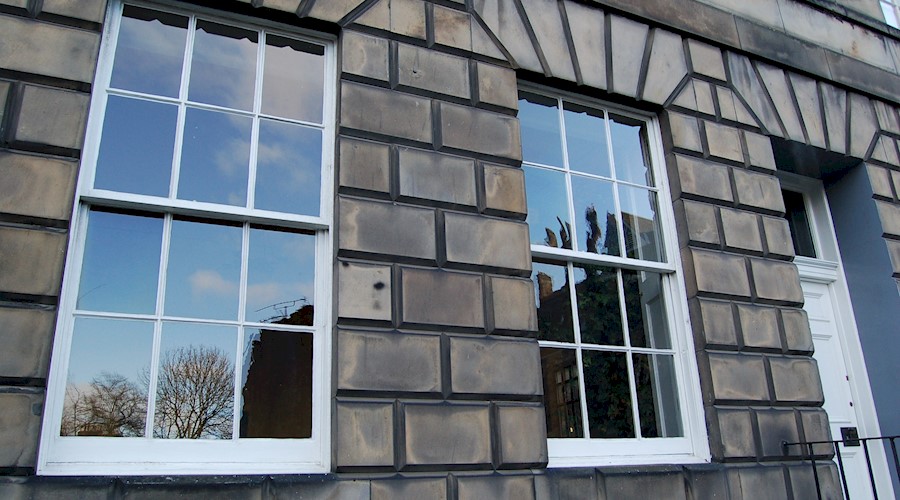 Two sash and case windows in a blonde sandstone tenement 
