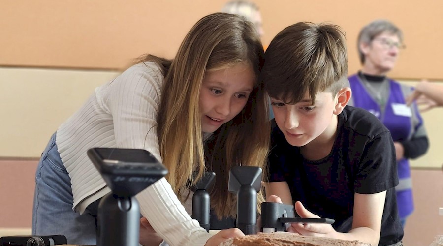 Two children examining a brick on a table