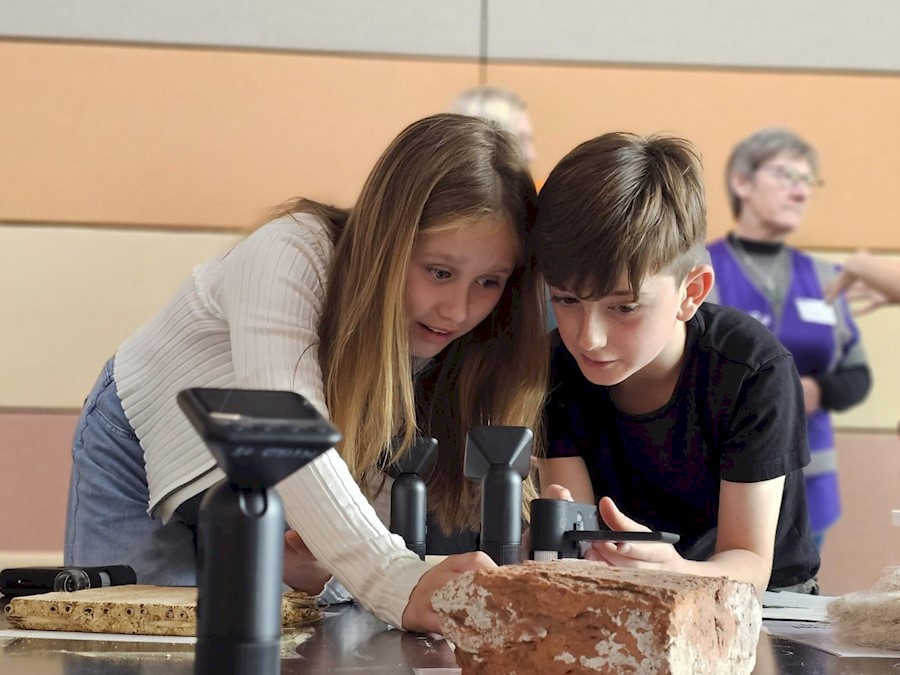 Two children examining a brick on a table