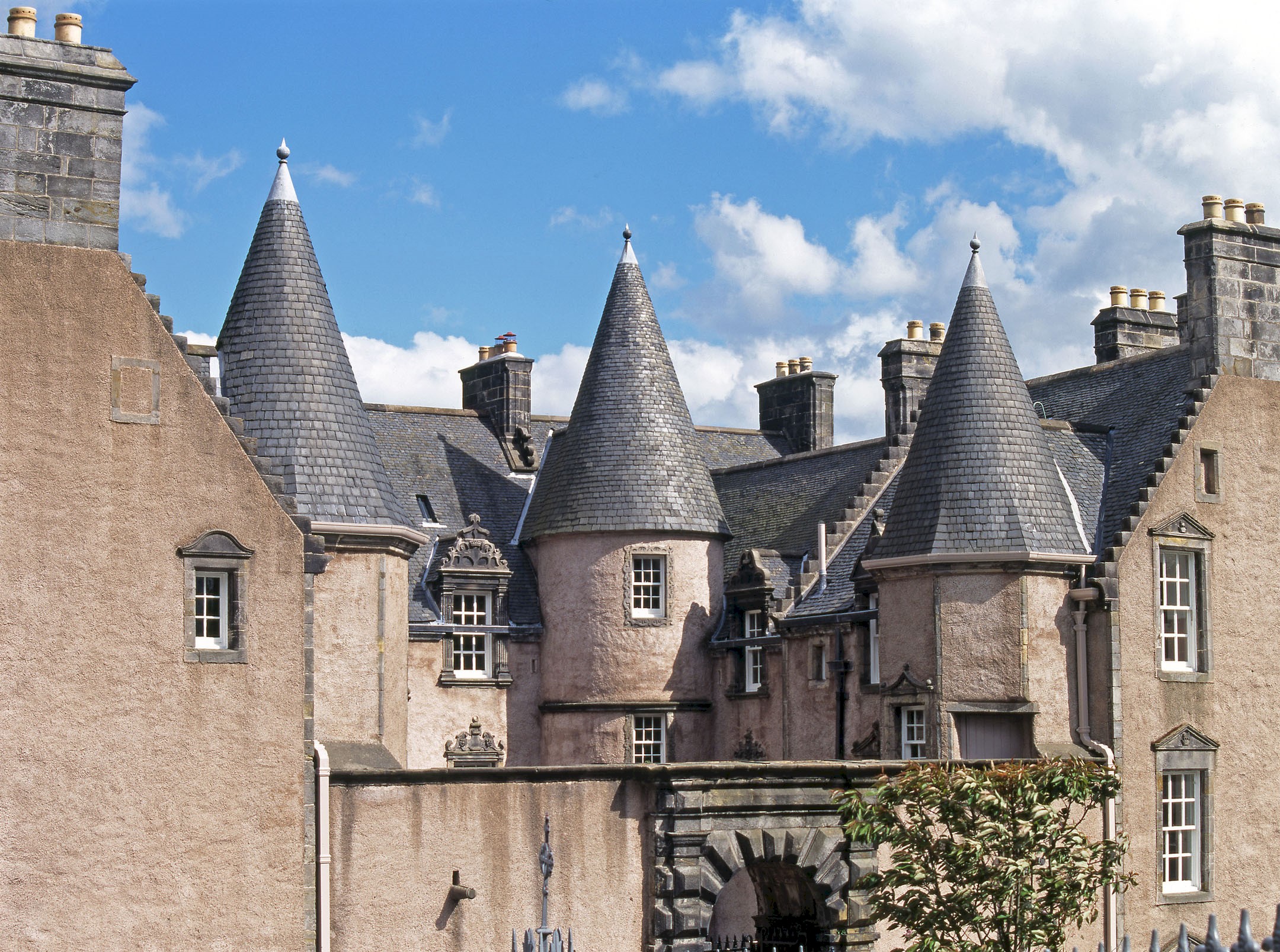 A large, traditional building with a slate roof featuring multiple turrets 
